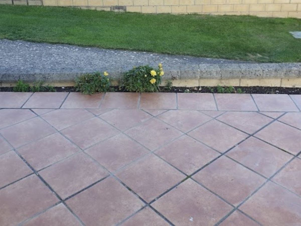 Terrasse extérieure carrelée en pose diagonale avec joints larges et bordure périphérique