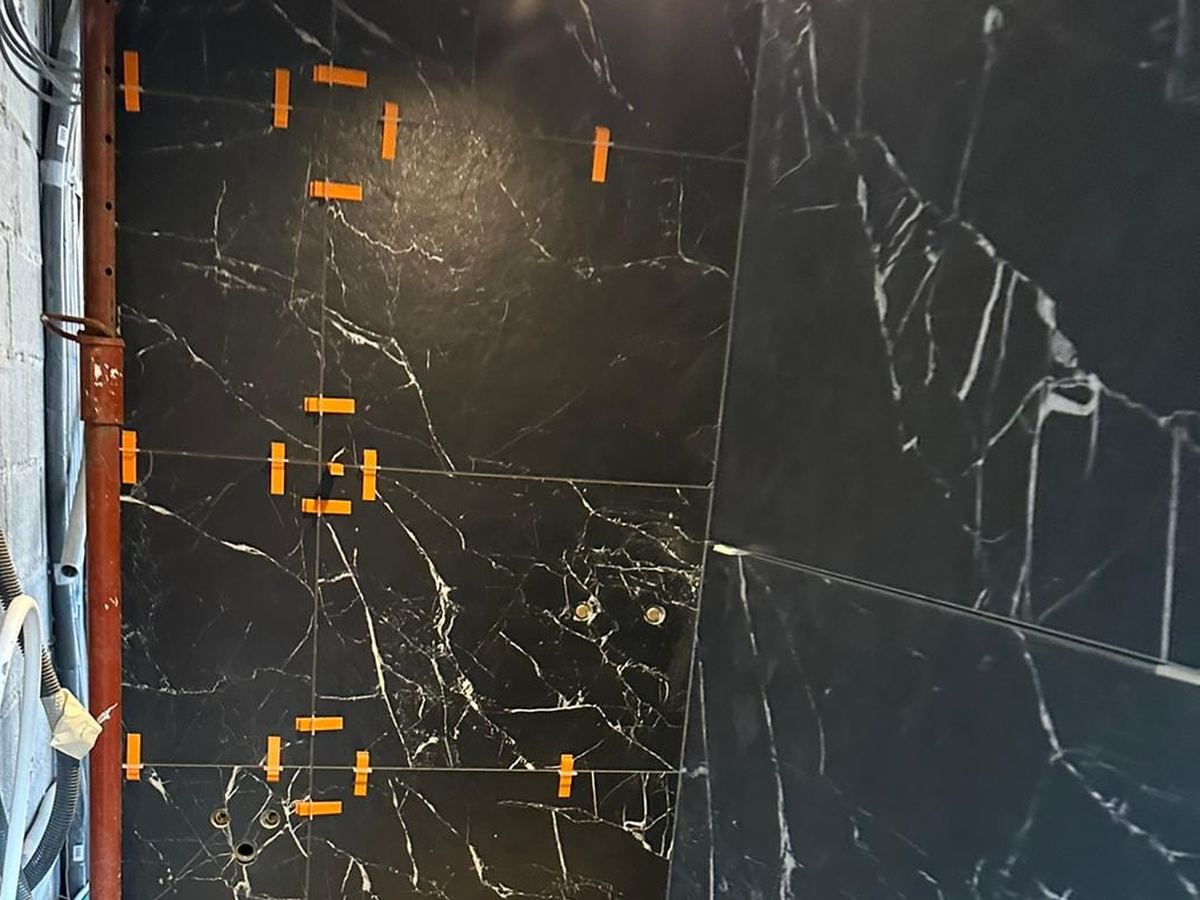 Carrelage grand format effet marbre noir posé au mur avec croisillons autonivelants orange