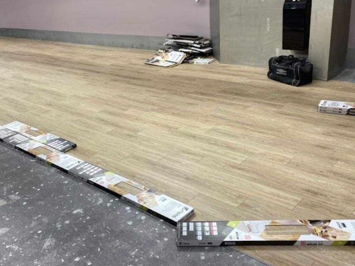 Pose d'un sol stratifié à lames rigides en cours dans un local commercial